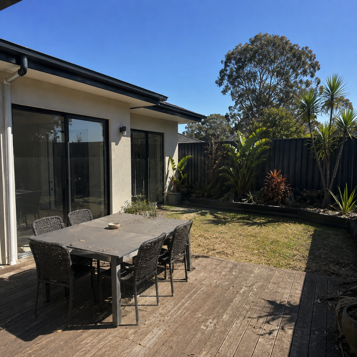 Terrasse en plein soleil avant la pose de la voile d'ombrage, mobilier inutilisé