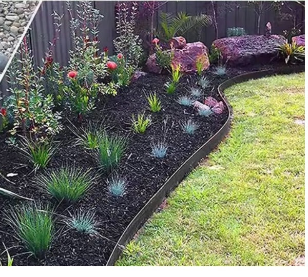 Black garden edging curving between a mulched native garden bed and lawn